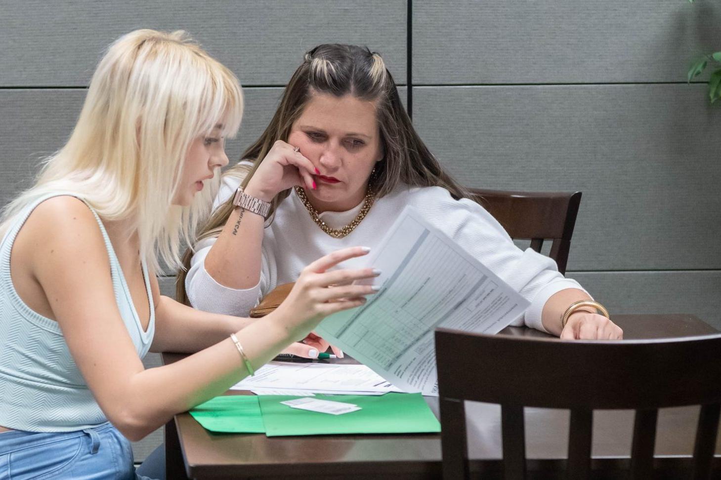 Student with parent in office setting, reviewing financial aid information together.